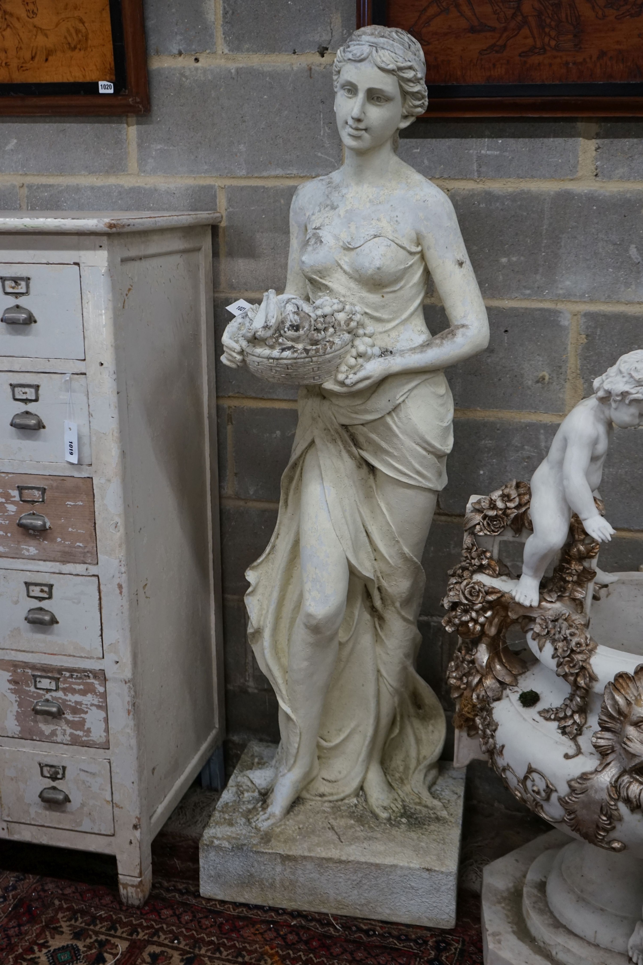 A large painted composition faux marble garden ornament, modelled as a girl with basket of fruit, height 160cm